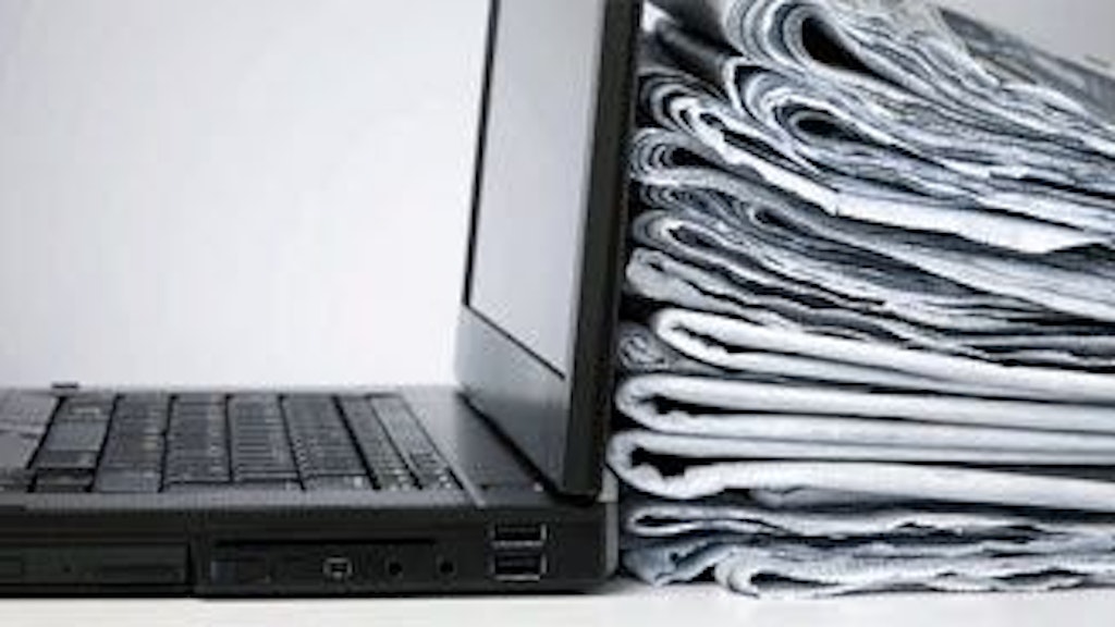 Ein Stapel zusammengefalteter Zeitungen lehnt an einen aufgeklappten schwarzen Laptop.