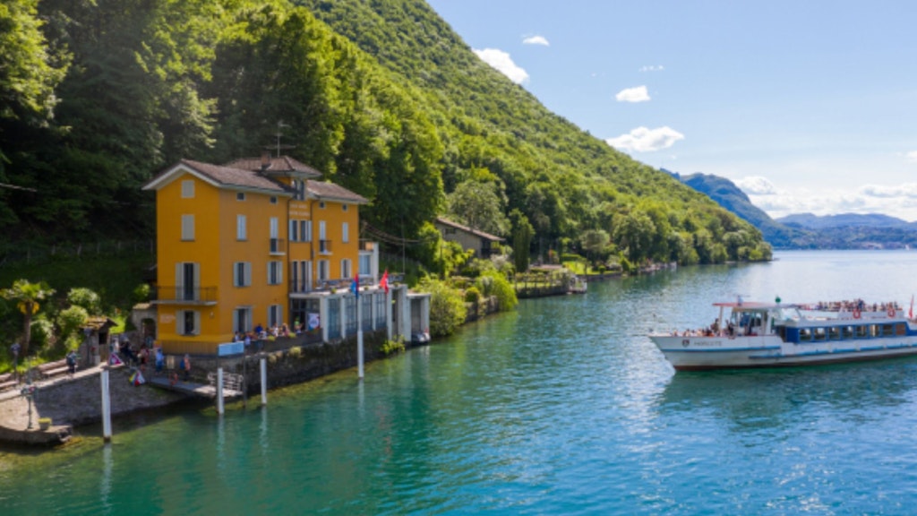 Un bateau passe devant un bâtiment jaune au bord d'un lac.