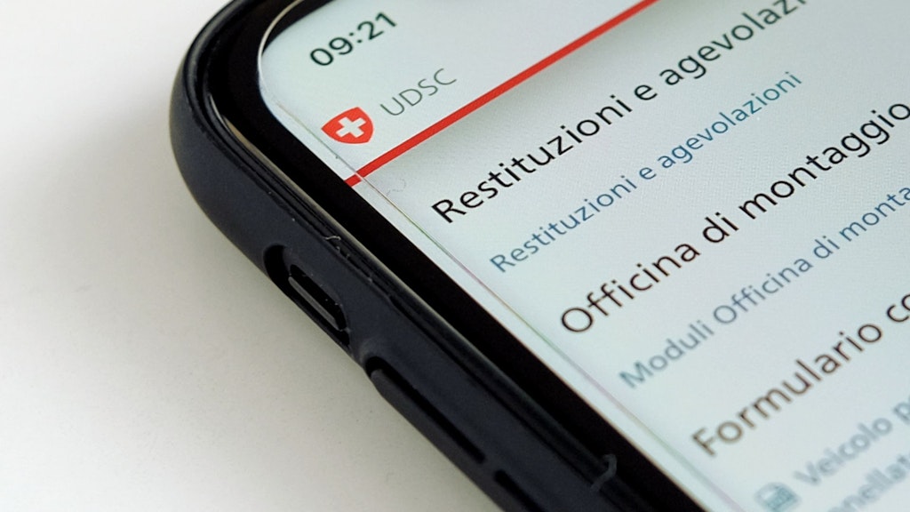 Uno smartphone nero è appoggiato su una superficie bianca. Lo schermo mostra una parte della pagina delle pubblicazioni della tassa sui veicoli pesanti (TTPCP).