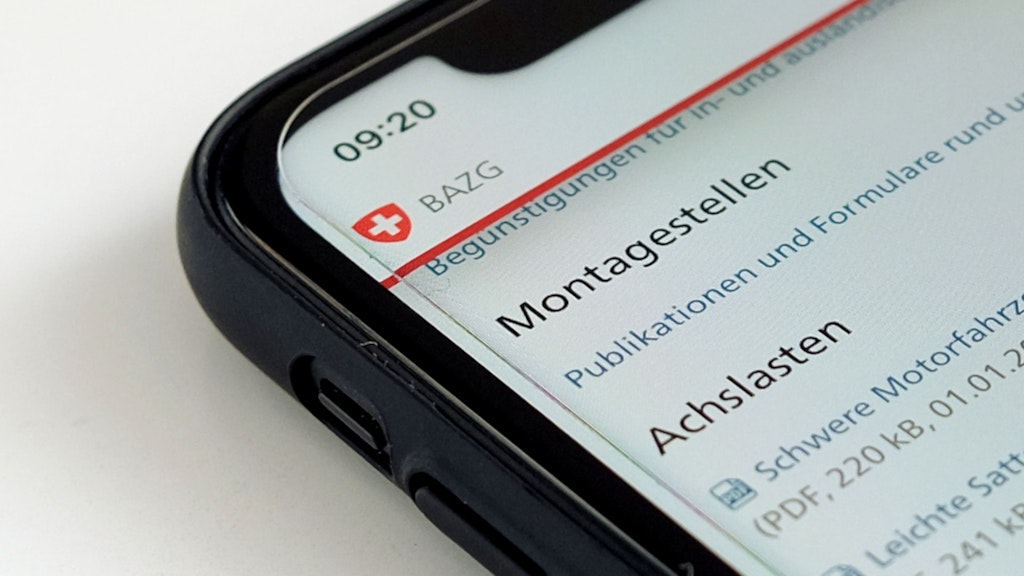 Ein schwarzes Smartphone liegt auf einer weissen Unterlage. Auf dem Bildschirm ist ein Teil der Seite Publikationen Schwerverkehrsabgaben LSVA zu sehen.