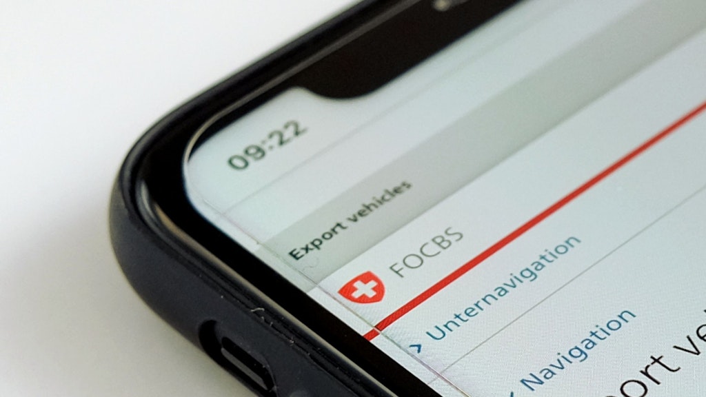 A black smartphone lies on a white surface. The screen shows part of the Heavy Goods Vehicle Fee (HVF) publications page.