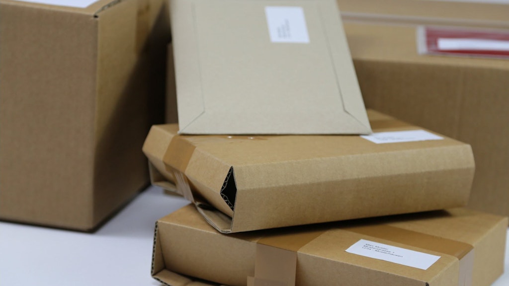 Several brown packages with address labels are stacked on top of each other. The packages are prepared for sending. 
