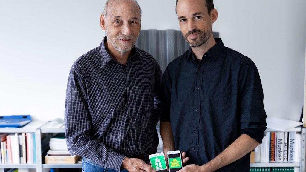 Zwei Personen halten nebeneinander eine Schweizer Autobahnvignette 2024 als Klebevignette in der Hand und als E-Vignette auf dem Smartphone. Die gruenen Symbole zeigen das Autobahnzeichen und die Jahreszahl 24.  