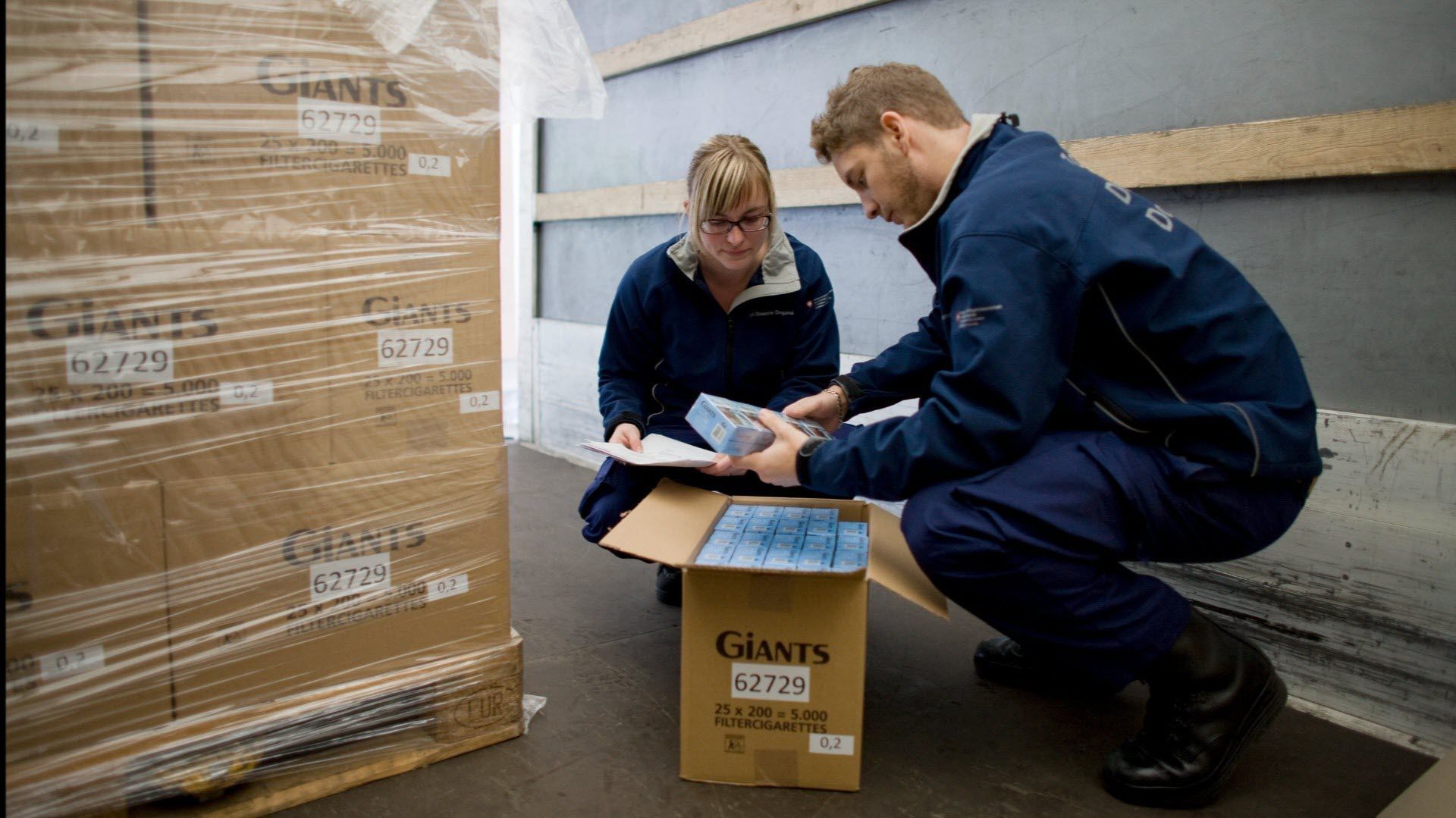 Zwei Personen kontrollieren Zigarettenlieferung in Lastwagen