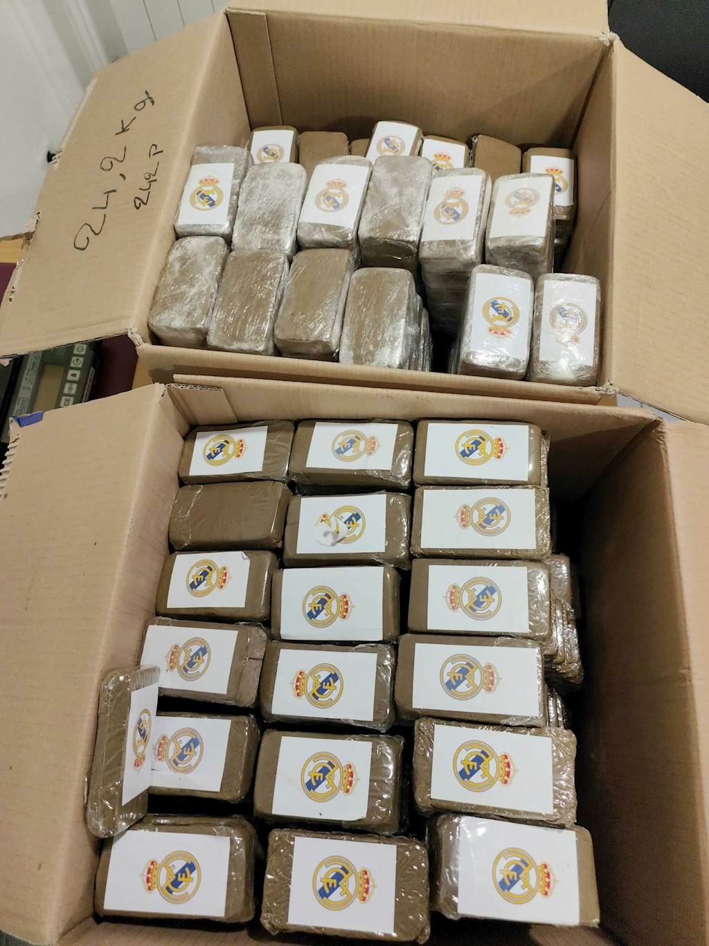 Zwei Kartons mit mehreren Paketen, die mit einem Logo versehen sind. Die Pakete enthalten CBD mit synthetischen Cannabinoiden.