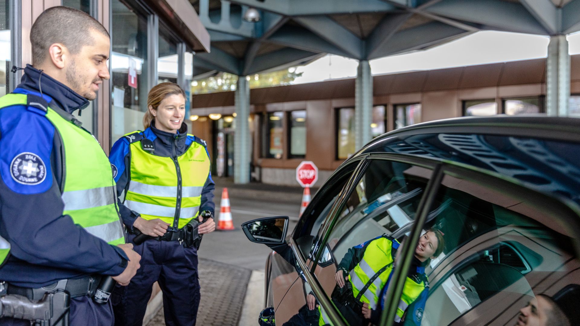 Zwei Mitarbeitende des Schweizer Zolls stehen neben einem schwarzen Fahrzeug
