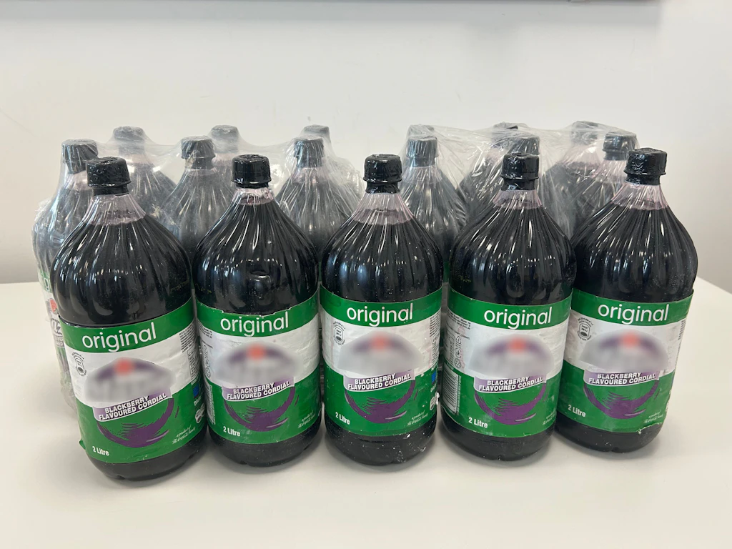 Mehrere Flaschen stehen nebeneinander auf einem Tisch. Die Flaschen sind in Plastikfolie verpackt und haben ein grünes Etikett mit der Aufschrift "original".