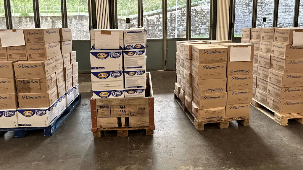 Mehrere Paletten mit Kartons voller Pommes frites stehen in einer Halle. Die Kartons wurden im Rahmen einer Kontrolle konfisziert, da mehrere Tonnen geschmuggelt wurden. Die Verpackungen sind mit Marken wie Aviko und Premium beschriftet.