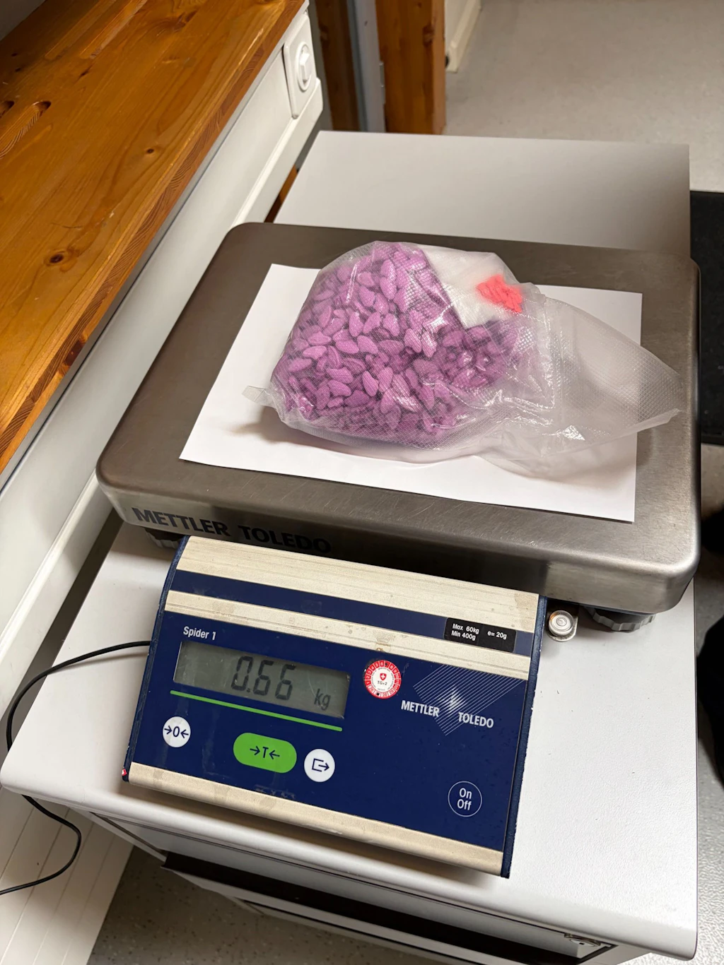 Ein verschlossener Plastikbeutel mit zahlreichen lilafarbenen Tabletten mit mutmasslichem Ecstasy wird auf einer Waage gewogen. Das Display der Waage zeigt ein Gewicht von 0.66 kg an. 