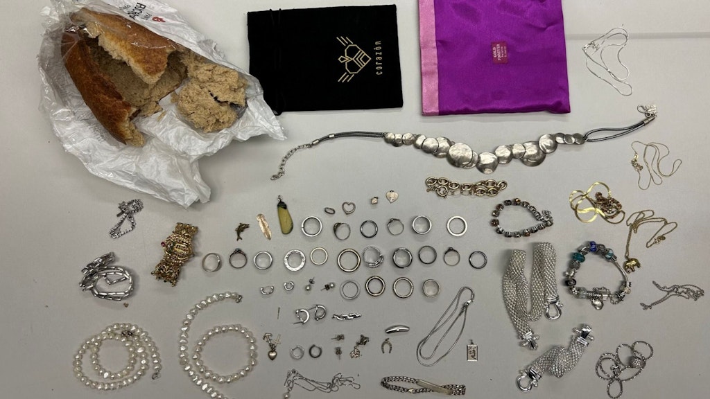 Eine Sammlung von Schmuckstücken, darunter Ringe, Armbänder und Ketten, liegt auf einem Tisch.