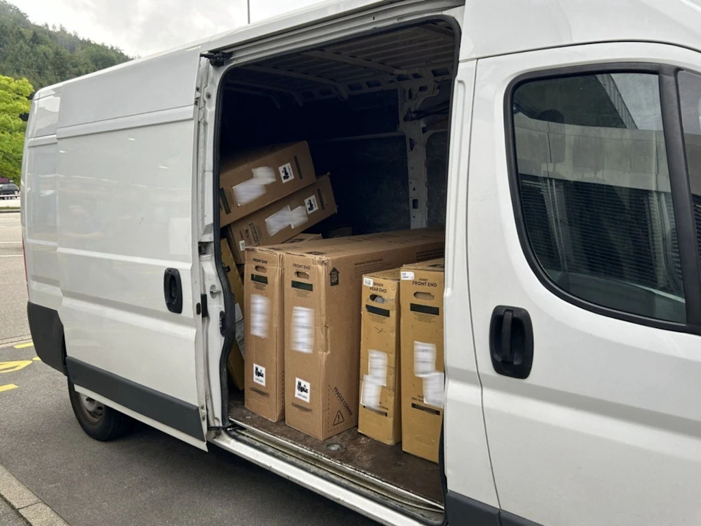 Ein geöffneter weisser Lieferwagen steht am Strassenrand. Im Laderaum sind zahlreiche Kartonschachteln mit Fahrrädern sichtbar, die offenbar gestohlen wurden.