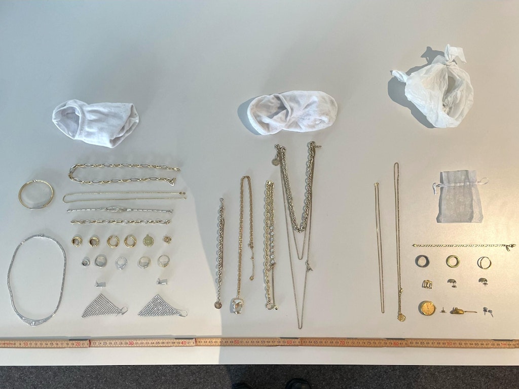 Eine Sammlung von Schmuckstücken, darunter Ketten, Ringe und Armbänder, liegen geordnet auf einem Tisch.