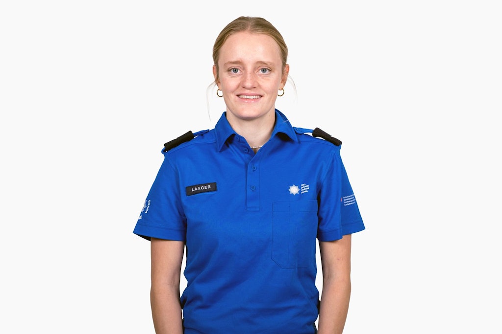Eine Mitarbeiterin des BAZG in blauer Uniform mit Namensschild "Laager". Sie trägt eine Uniform mit Abzeichen des BAZG.