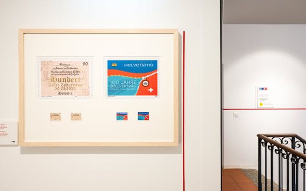 An exhibition frame at the Swiss Customs Museum displays documents and stamps celebrating 100 years of the customs agreement between Switzerland and Liechtenstein.