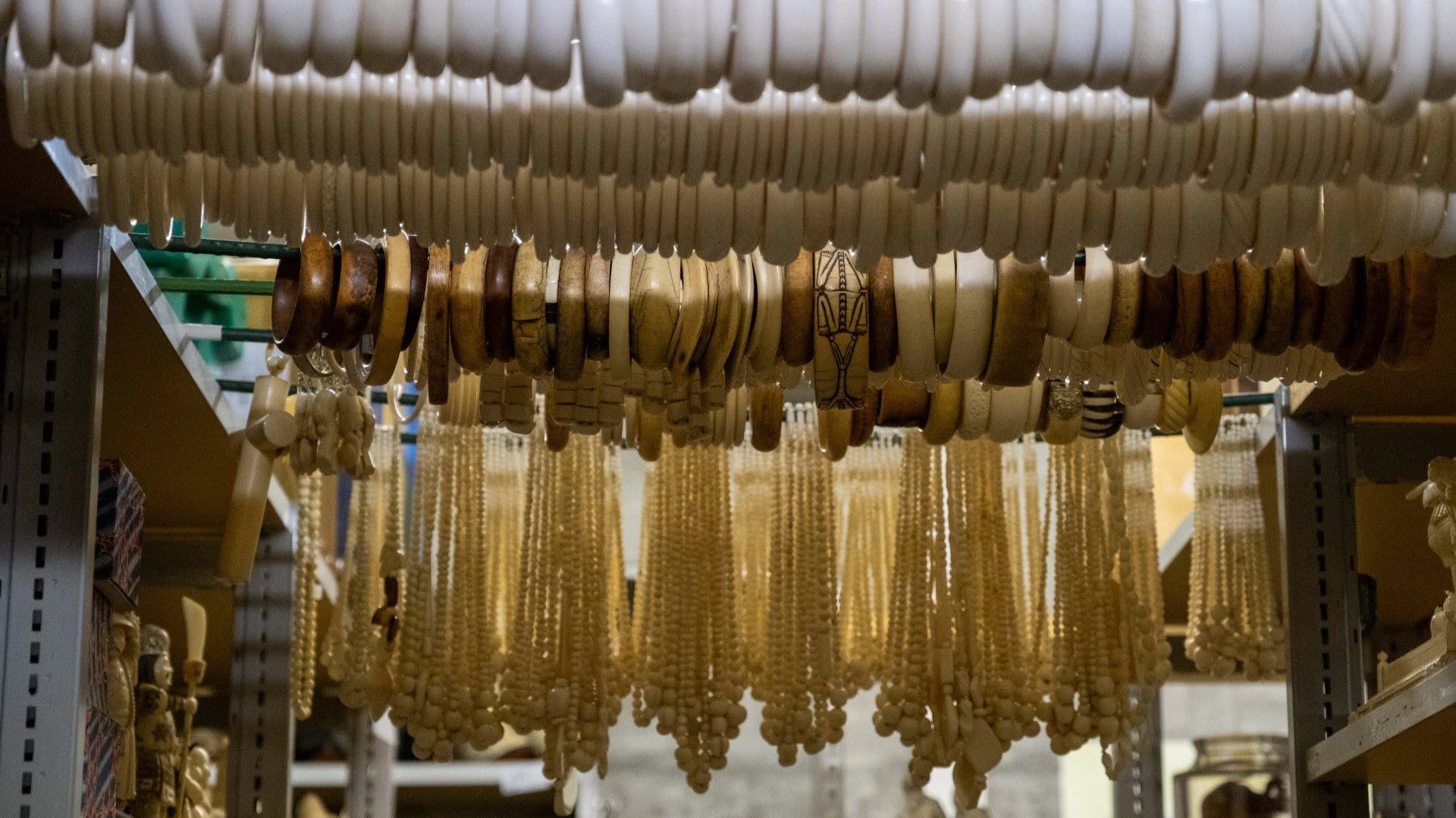 Une étagère avec divers bijoux, y compris des bracelets et des colliers suspendus à des crochets. Les bijoux semblent être fabriqués à partir de matériaux différents.