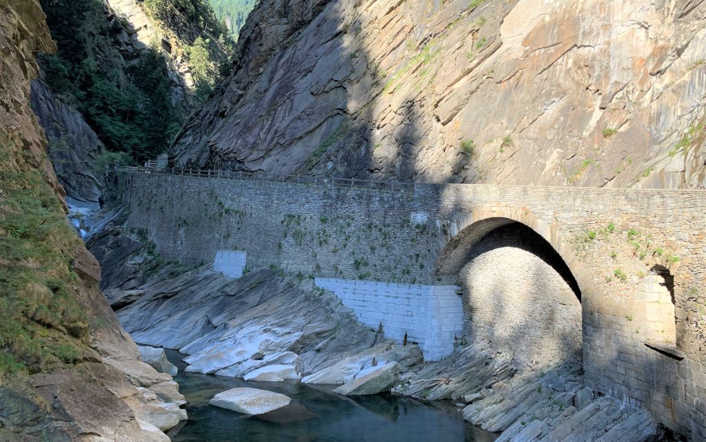 Un vieux pont en pierre s'étend sur une étroite gorge aux parois rocheuses abruptes.