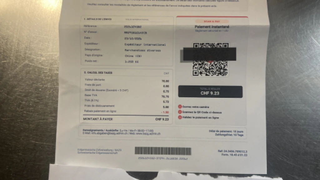 Une fausse lettre prétendant provenir de la douane suisse est ouverte sur une table. La lettre mentionne une prétendue procédure de dédouanement et demande un paiement via un QR-Code. En dessous se trouve une enveloppe à fenêtre.