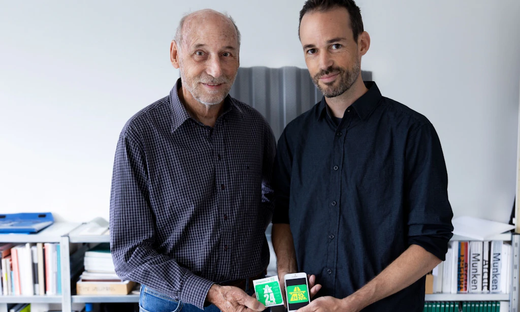 Deux personnes présentent côte à côte la vignette autoroutière suisse 2024 sous forme de vignette autocollante et de e-vignette sur un smartphone. Les symboles verts montrent le panneau d’autoroute et l’année 24.  
