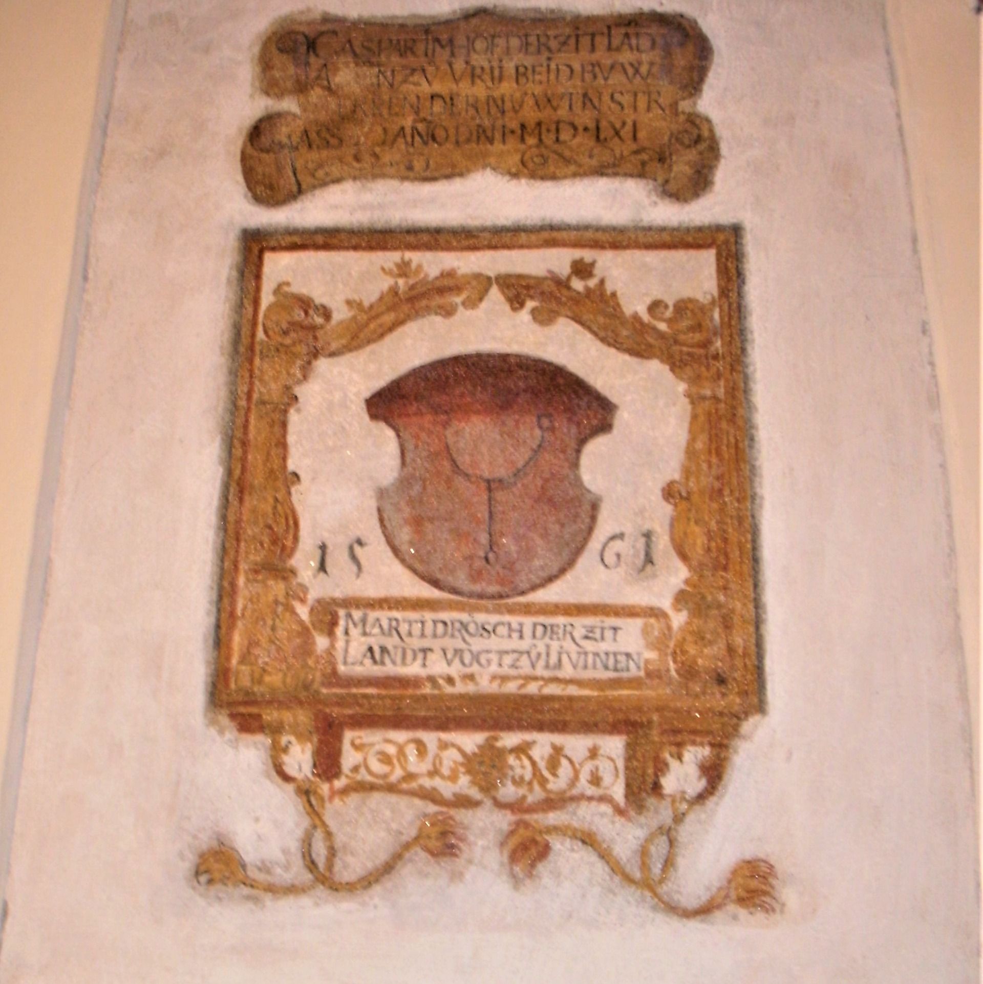 Un affresco storico con uno stemma e un'iscrizione. L'affresco mostra elementi decorativi e scritte in latino.  
