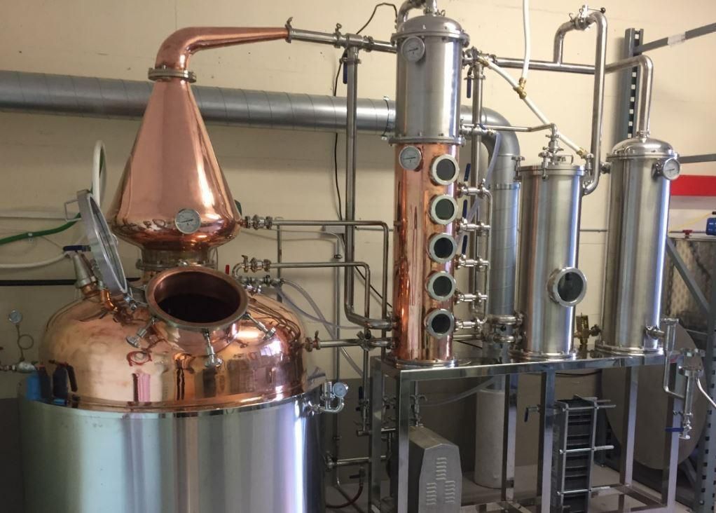 Un impianto di distillazione industriale in rame e acciaio inossidabile. È composto da diverse colonne e tubi utilizzati per la produzione di alcol.