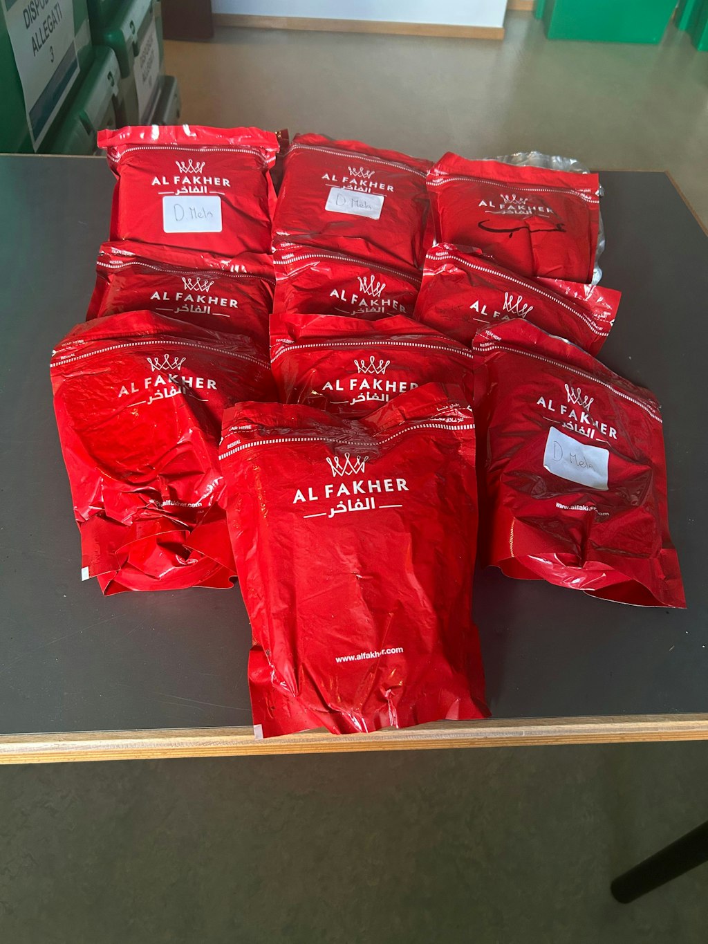 Diversi pacchetti rossi con la scritta "Al Fakher" sono su un tavolo. Questi pacchetti contengono tabacco per shisha e sono stati sequestrati dal'UDSC
